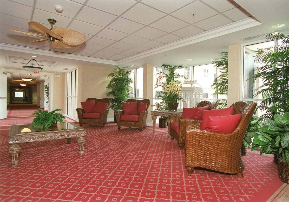 A comfortable hotel lobby with wicker furniture and vibrant red carpet.