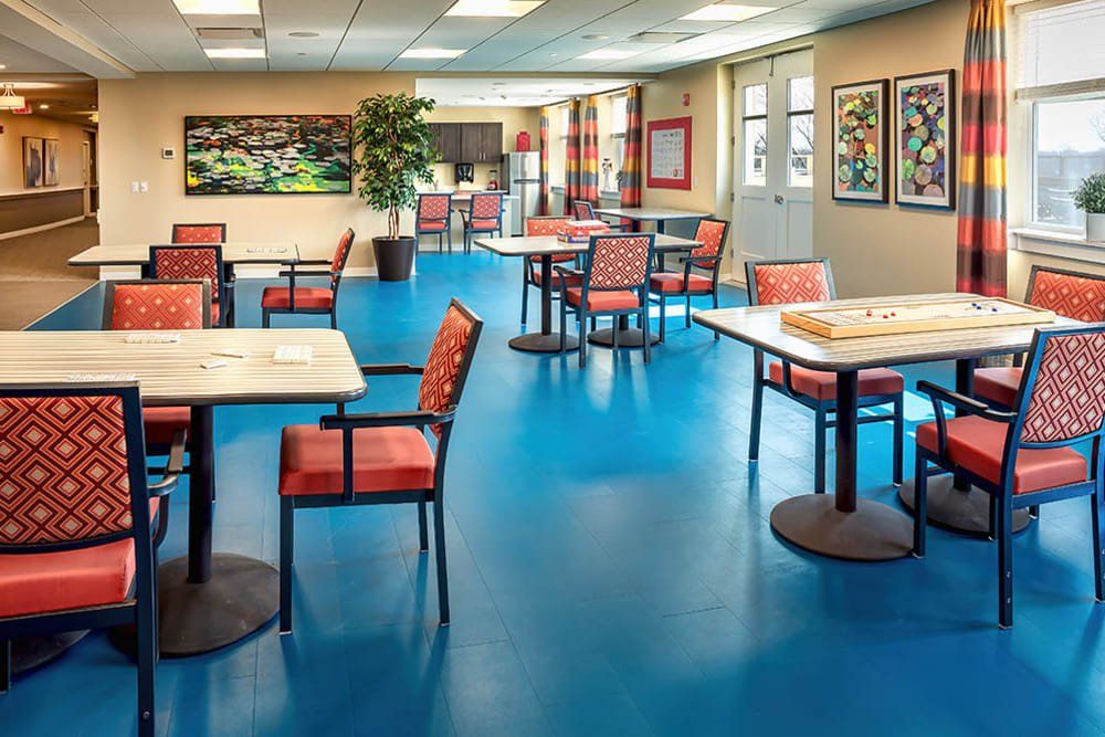 A modern cafeteria with colorful flooring and neatly arranged tables and chairs.