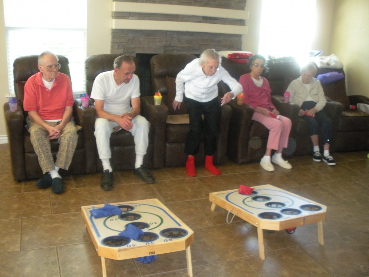 A group of seniors engaged in an indoor game activity, sitting in a row on couches.