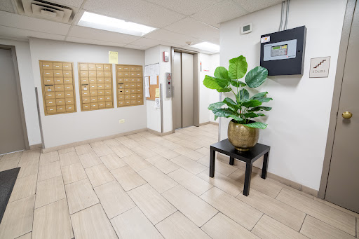 A modern lobby area featuring an elevator, mailboxes, and a decorative plant.