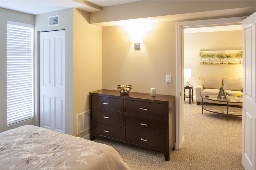 A cozy modern bedroom with a dark wood dresser and soft lighting.