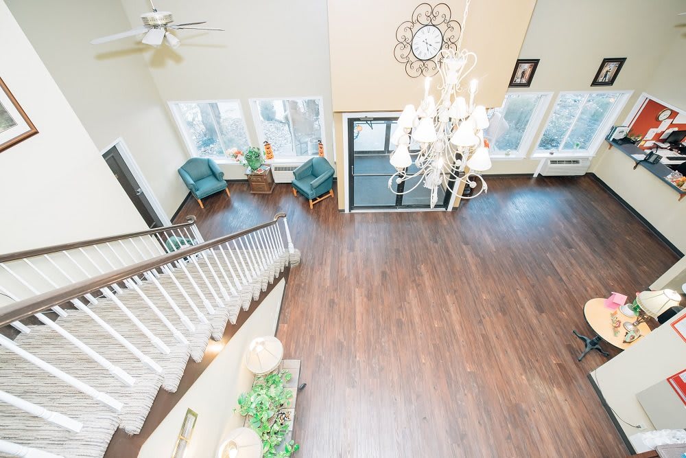 Spacious living room with hardwood floors and a large chandelier, featuring a seating area and staircase.