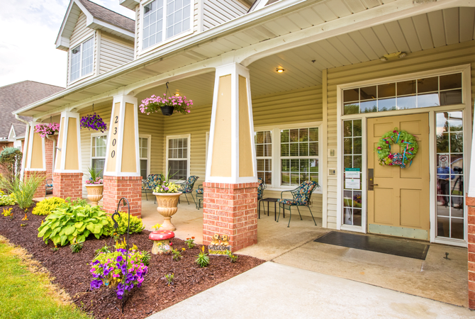 A welcoming front porch of a house adorned with flowers and landscaping.