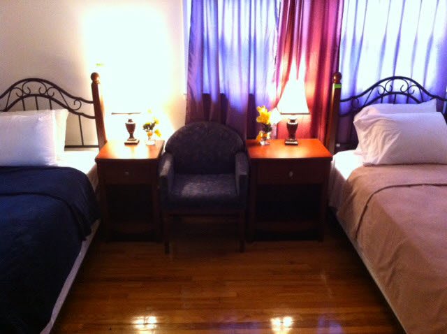 A cozy bedroom with two twin beds, nightstands, and lamps.