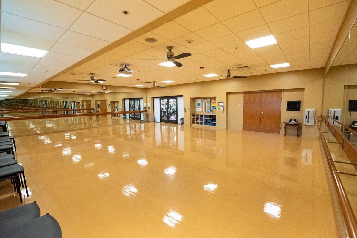 Spacious dance studio with wooden flooring and mirrored walls.