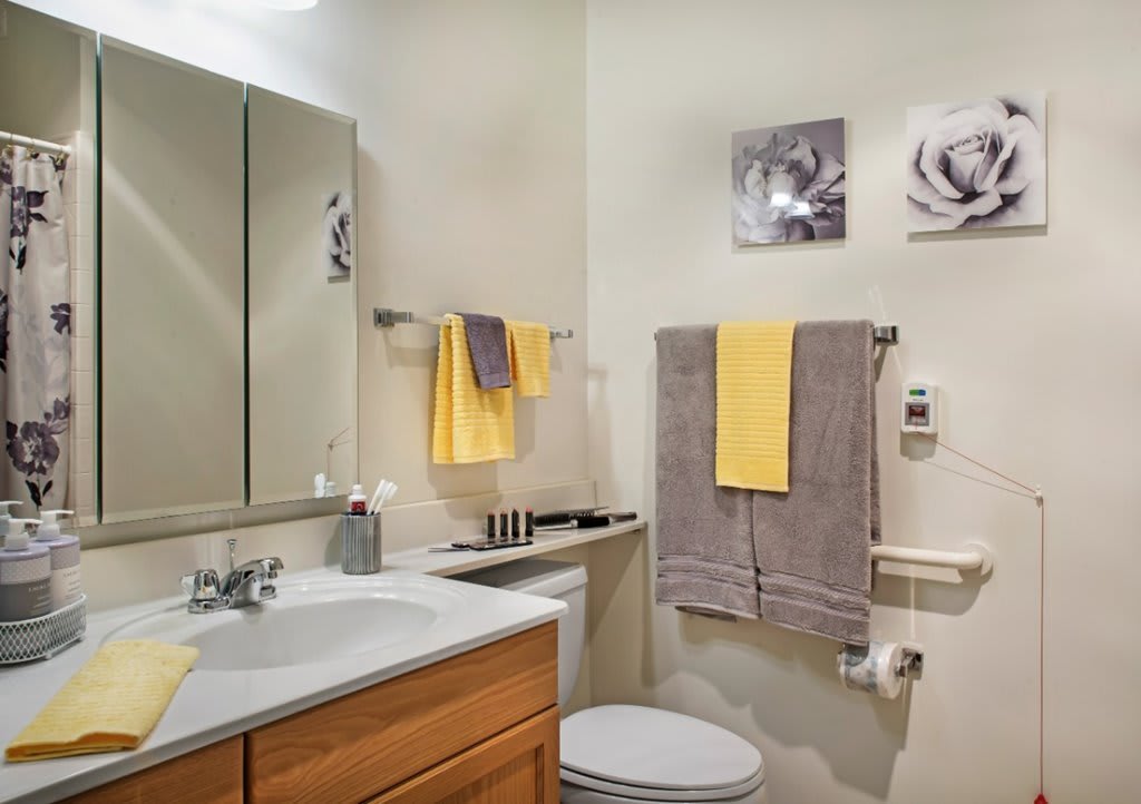 A modern bathroom featuring a sink, toilet, and decorative towels in yellow and gray.