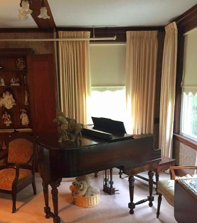 A serene living room featuring a grand piano, elegant curtains, and classic wooden furniture.