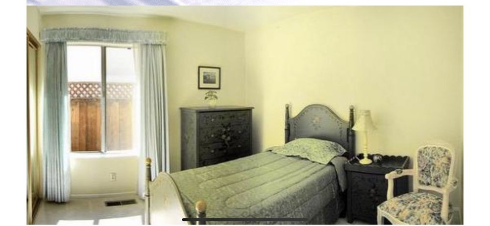 A minimalist bedroom featuring a single bed with a headboard, a dresser, and curtains.