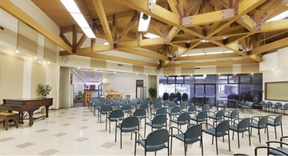 An empty auditorium with rows of chairs and a wooden ceiling.