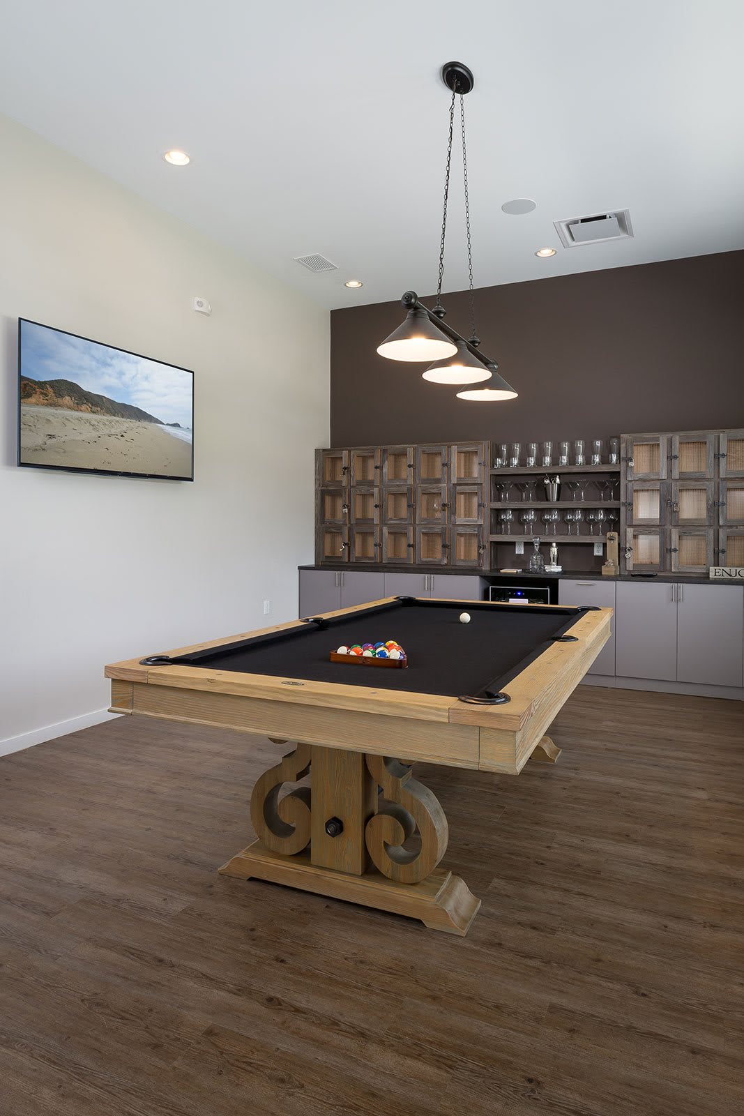 A modern game room featuring a billiards table with ornate wooden legs and contemporary decor.