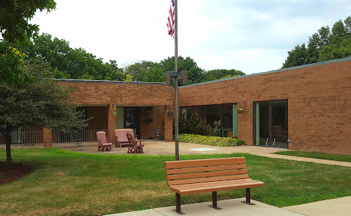 A serene outdoor seating area with a bench and a flagpole outside a brick building.