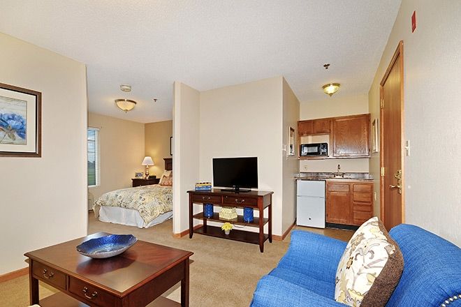 A cozy open-concept apartment featuring a living area, bedroom, and small kitchenette.