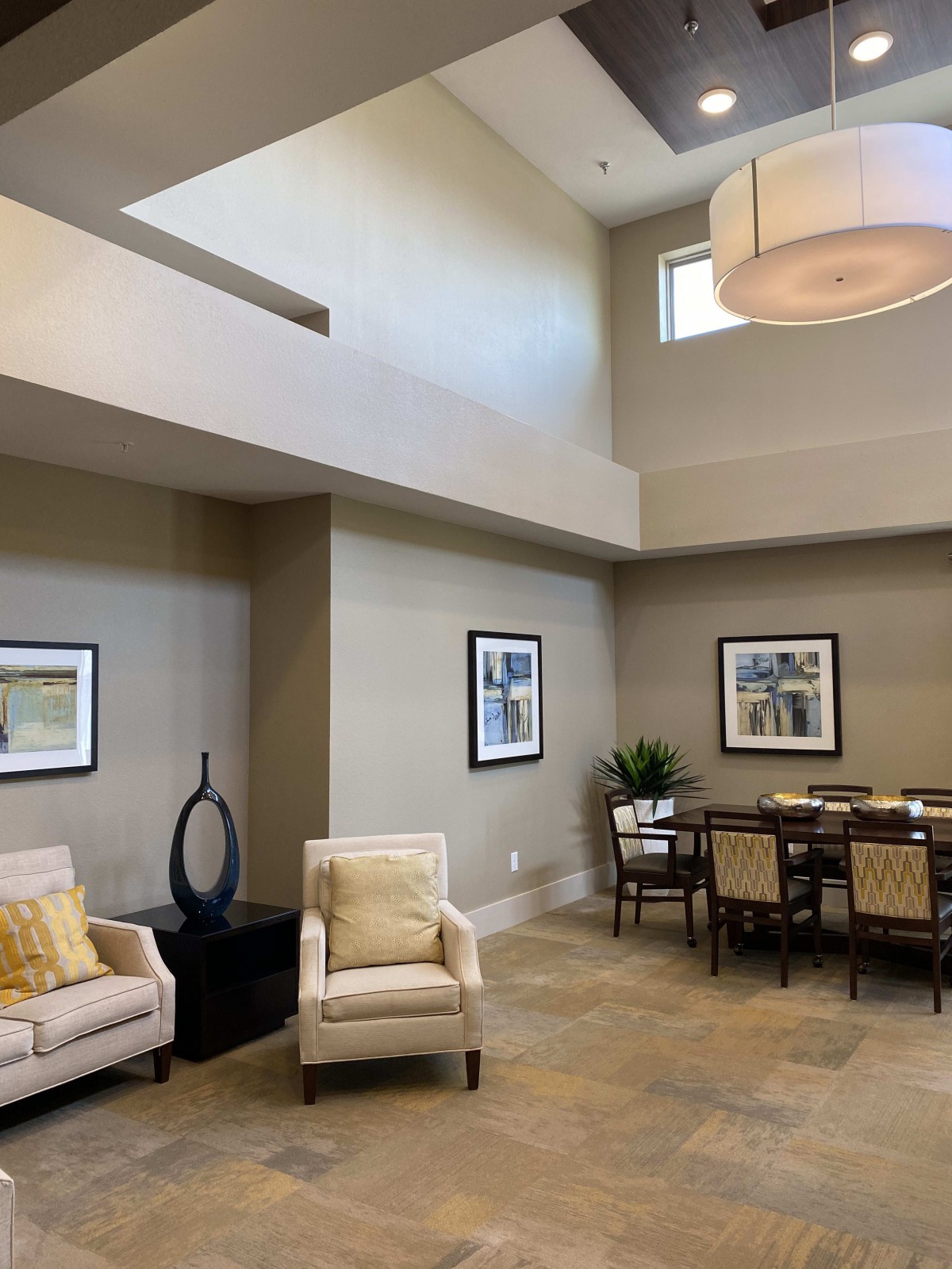 A modern interior with a combined living and dining area, featuring high ceilings and neutral tones.