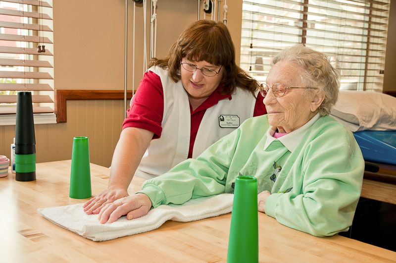 A caregiver assisting an elderly woman with physical therapy exercises.