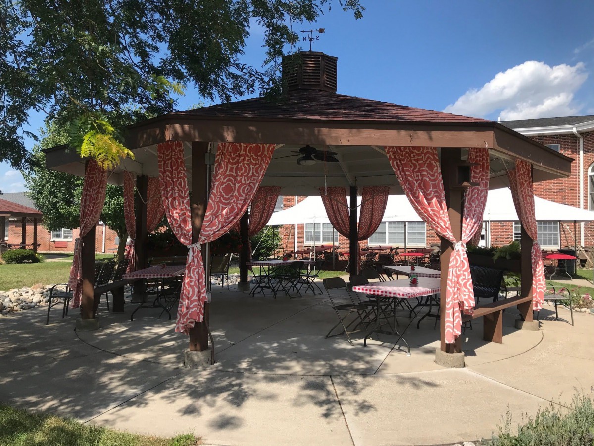 An outdoor gazebo with red curtains and patio furniture.