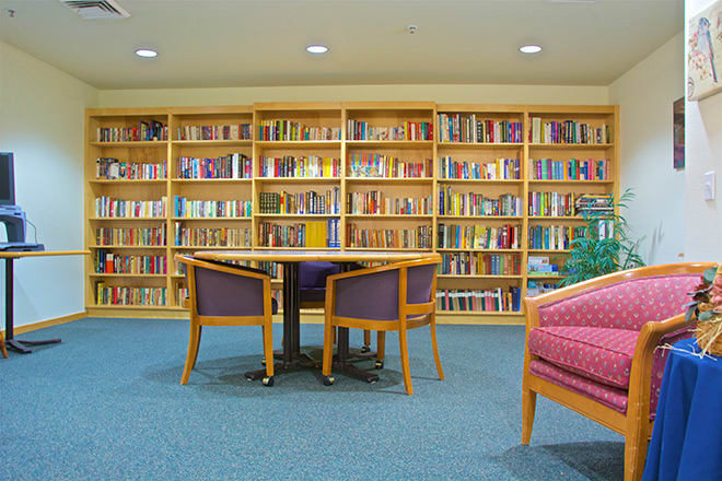 A cozy library space with shelves full of books and a small table surrounded by chairs.
