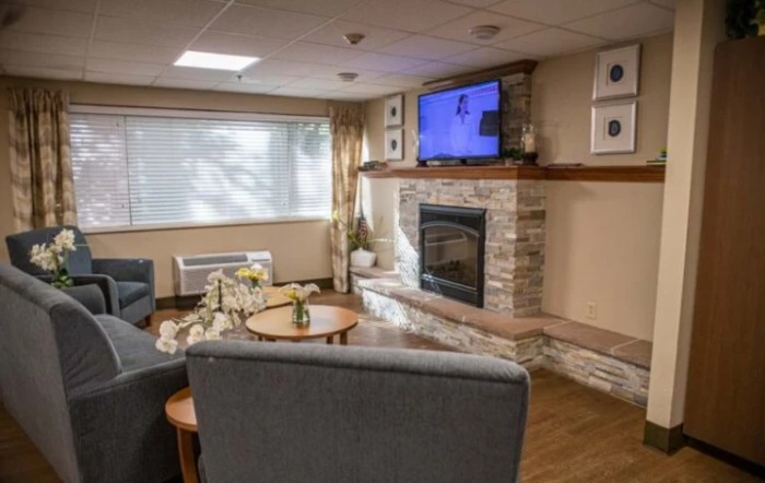 A cozy living room features a stone fireplace, modern furniture, and a wall-mounted television.