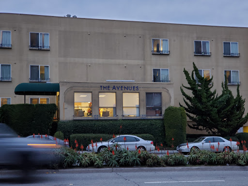 A view of a residential building at dusk, showcasing its architecture and nearby greenery.