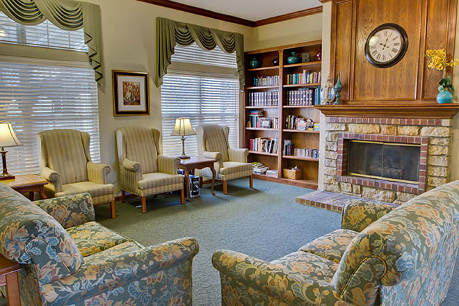A cozy living room with a fireplace, bookshelves, and comfortable seating.