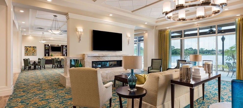 A modern living room with comfortable seating, a television mounted above the fireplace, and decorative lighting.