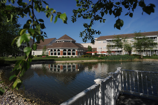 A serene view of a lakeside building reflecting in the calm waters, surrounded by lush greenery.