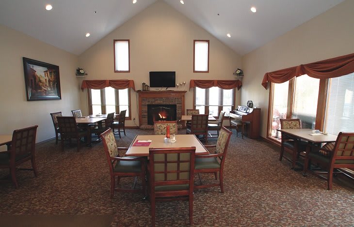 A cozy living room with a fireplace, tables, and chairs arranged for a communal setting.