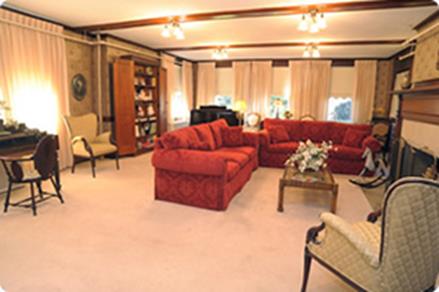 A cozy living room featuring a red sofa set, a bookshelf, and warm lighting.
