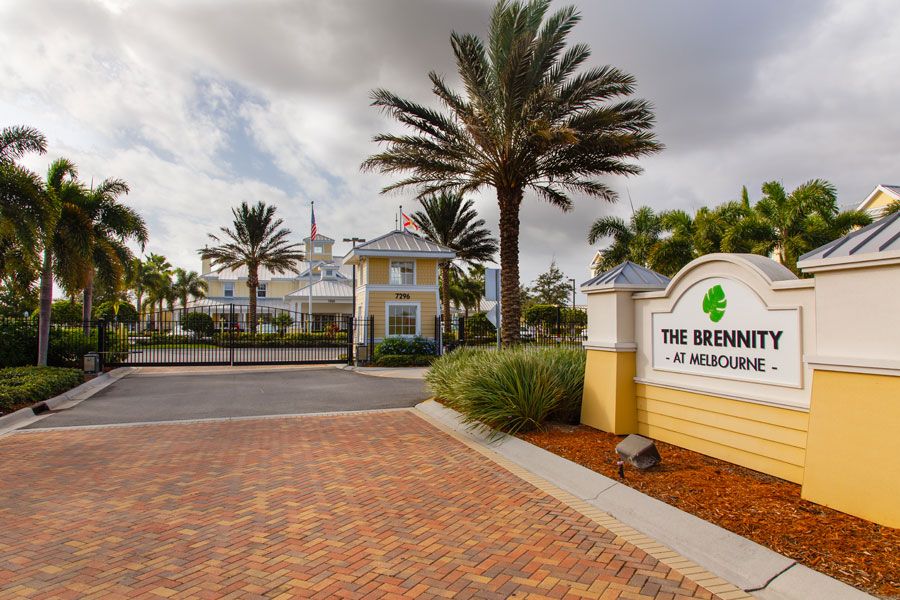 Entrance to a resort with palm trees and a welcoming sign.