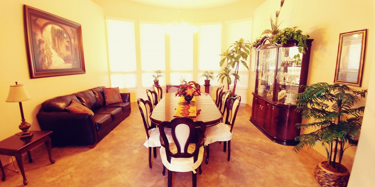 A well-lit dining room with a large table and chairs, adorned with floral decorations.