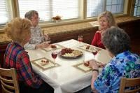 A group of people sitting around a table, enjoying a meal together.