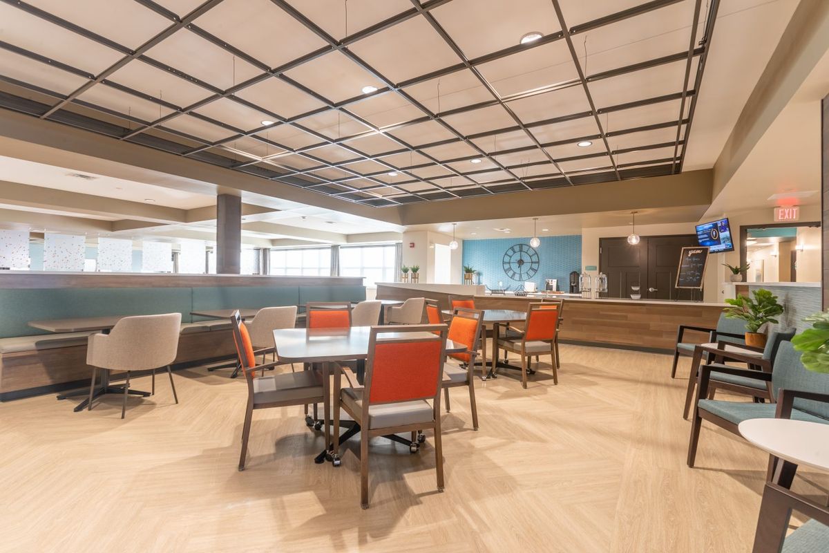 A modern dining area with tables and chairs, featuring a stylish ceiling design.