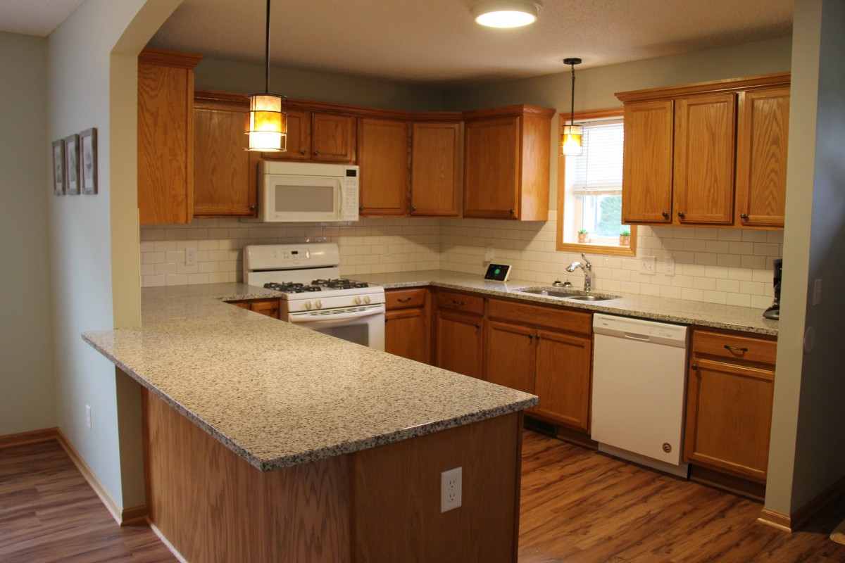 A modern kitchen with wooden cabinets, granite countertops, and stainless steel appliances.