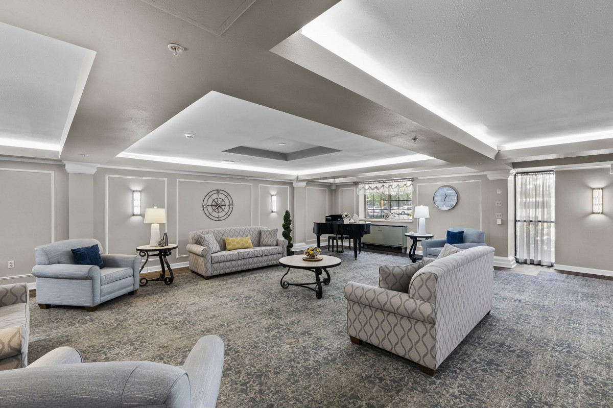 A spacious and elegantly designed living room featuring comfortable seating, a grand piano, and ambient lighting.