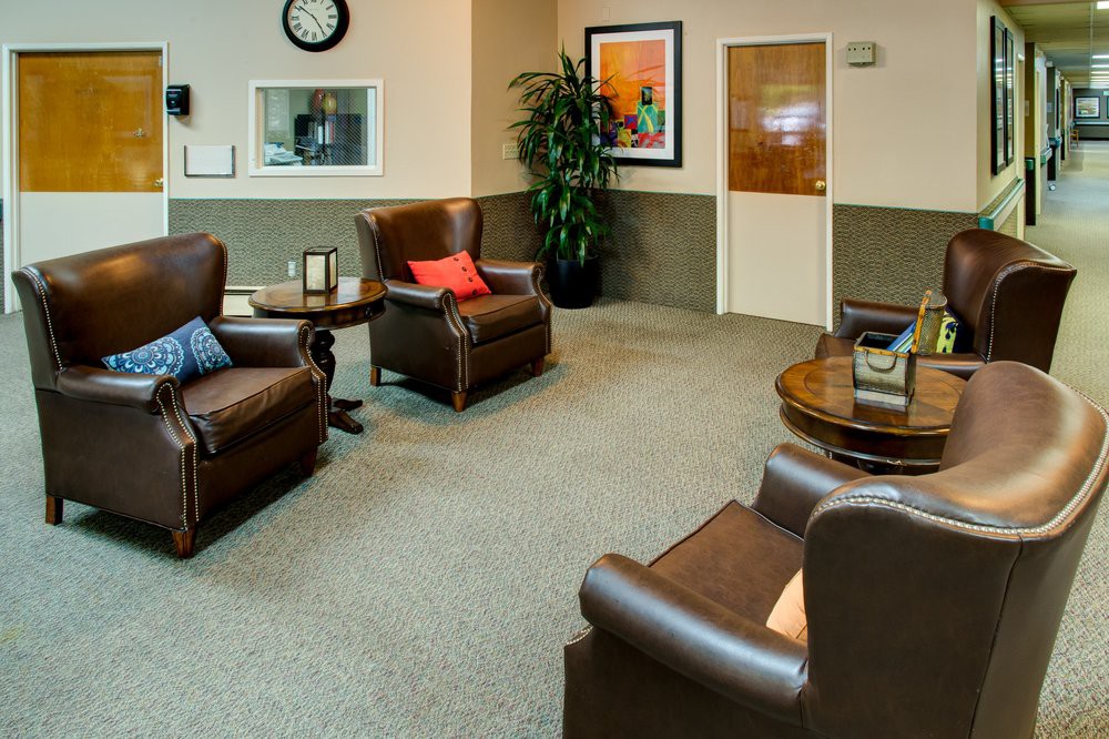 A cozy waiting room with leather chairs and a coffee table.