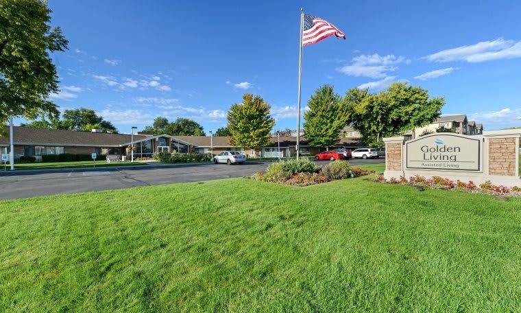 A well-maintained lawn with an American flag flying in front of a building on a clear day.