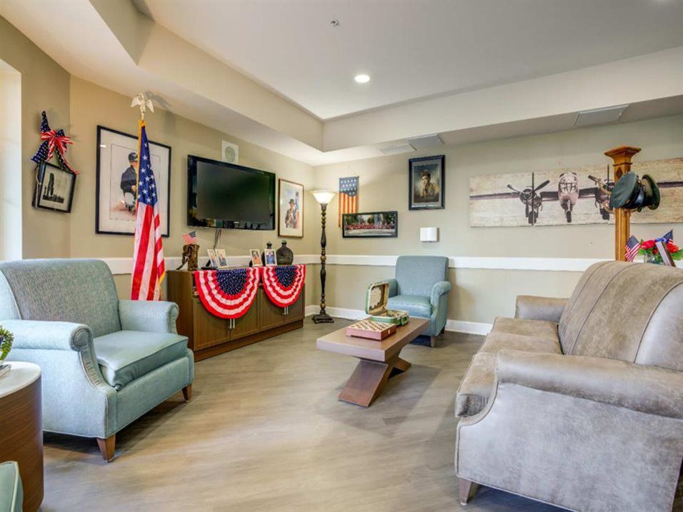 A cozy living room with a patriotic theme, featuring comfortable seating, a television, and American flag decor.