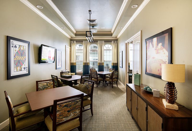 A well-lit dining area featuring multiple tables and chairs, decorated with elegant light fixtures and a wall-mounted television.