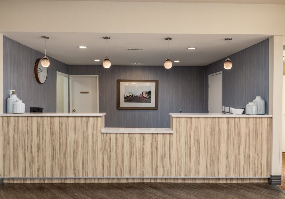 A modern reception desk area with overhead lights and a painting on the wall.