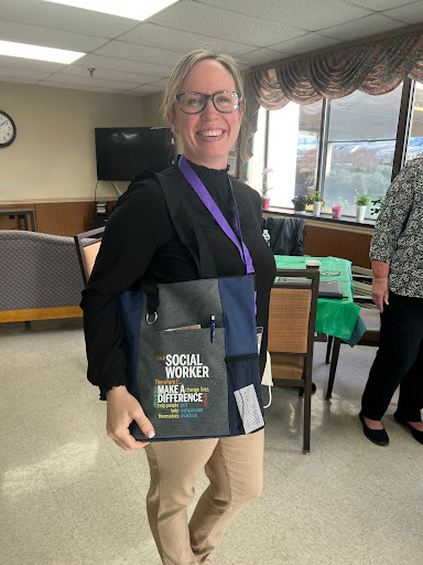 A smiling woman at an event, proudly holding a tote bag promoting social advocacy.