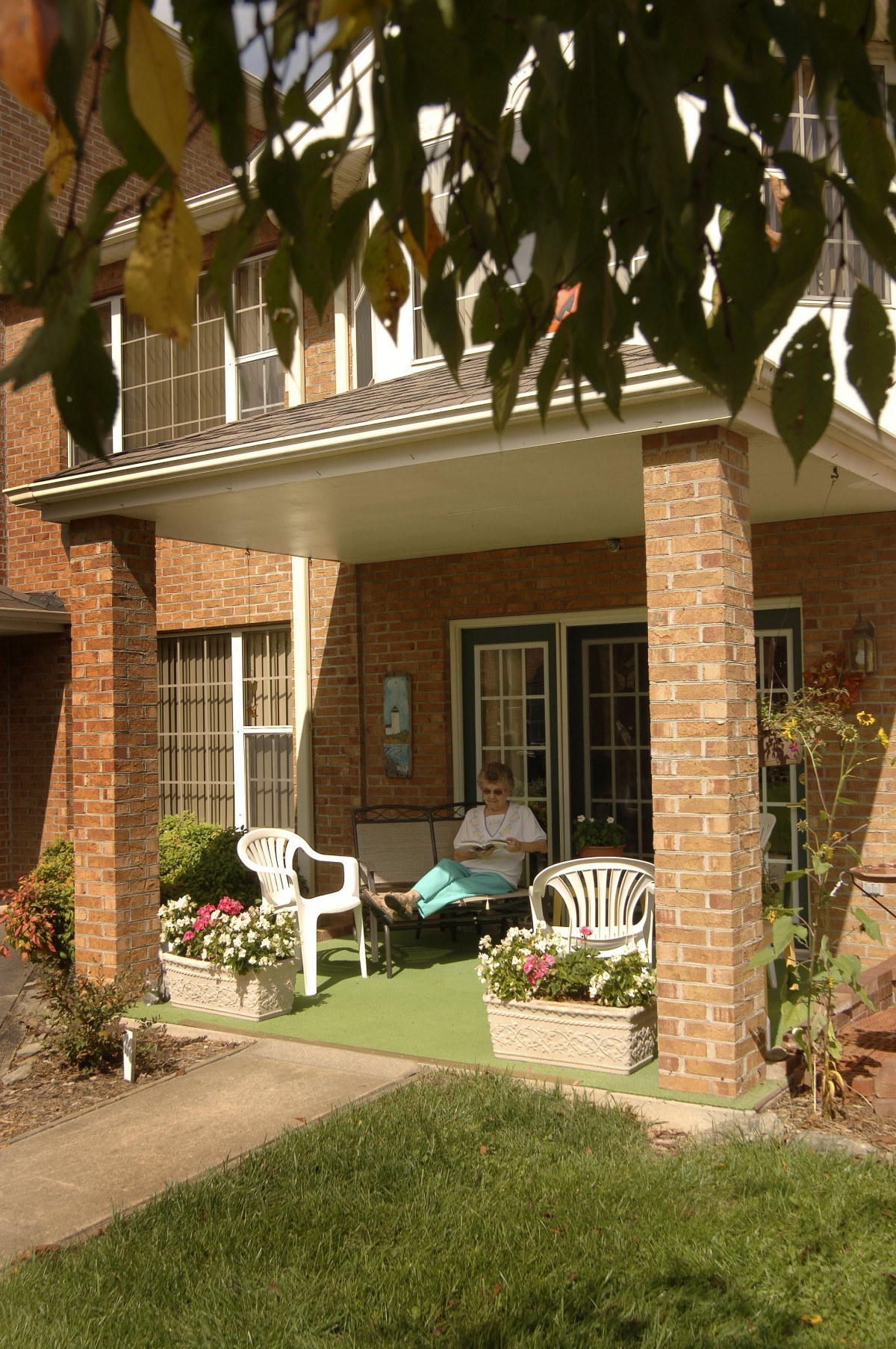 A cozy porch with chairs and plants at the entrance of a brick house.
