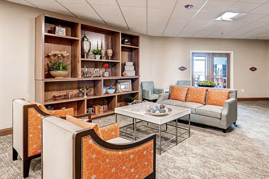 A well-decorated living room with a sectional couch, coffee table, and shelving.