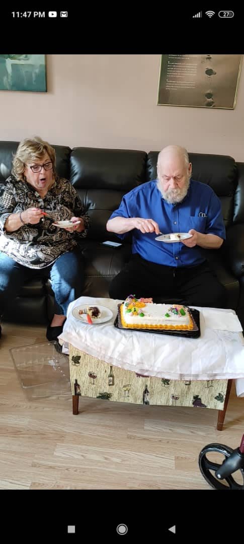Two people enjoying a cake during a celebration in the living room.