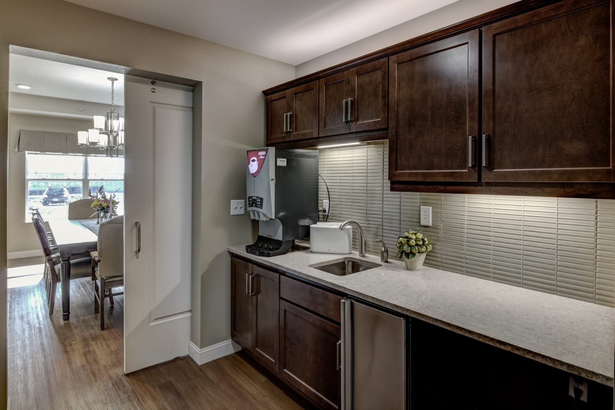 A modern kitchen with dark cabinets, a countertop with a sink, and various appliances.