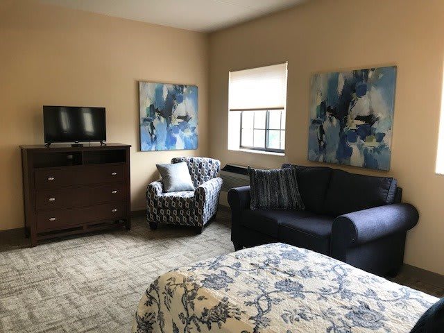 A cozy living room with modern furniture, abstract artwork, and a television.
