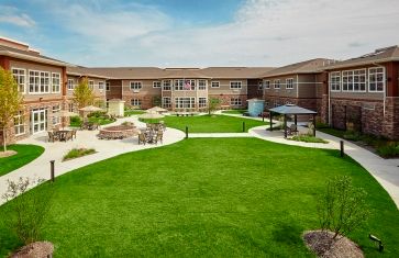 A well-maintained courtyard with green lawns and winding pathways, surrounded by a two-story brick building.
