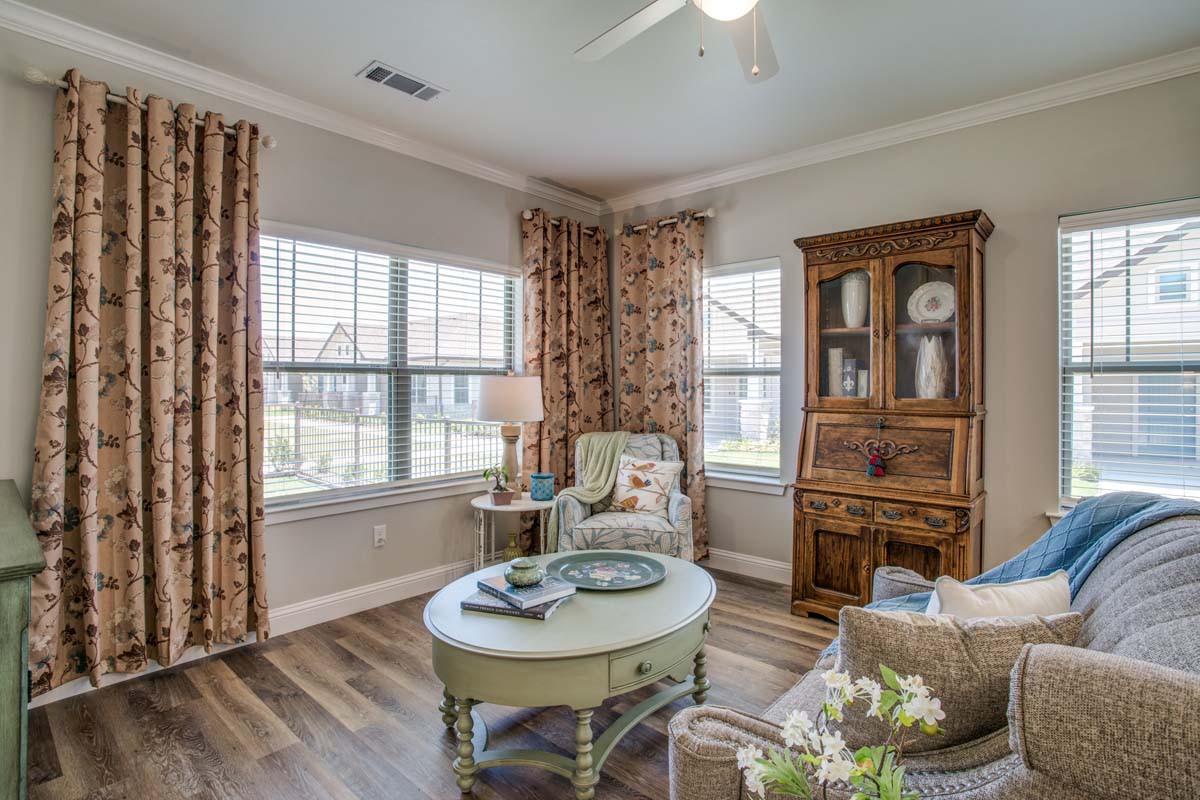 A cozy living room with a wooden cabinet, armchair, and coffee table by the window.