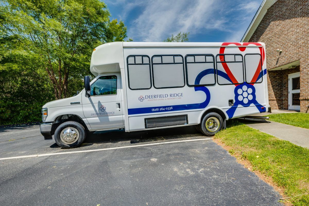 A white shuttle bus parked on a paved surface with trees in the background.