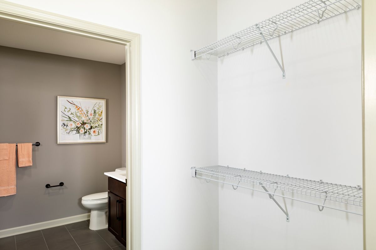 A view of a closet space leading into a modern bathroom with decorative wall art.