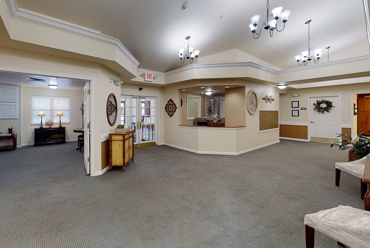 A spacious lobby with a reception desk, chandeliers, and decorative elements.