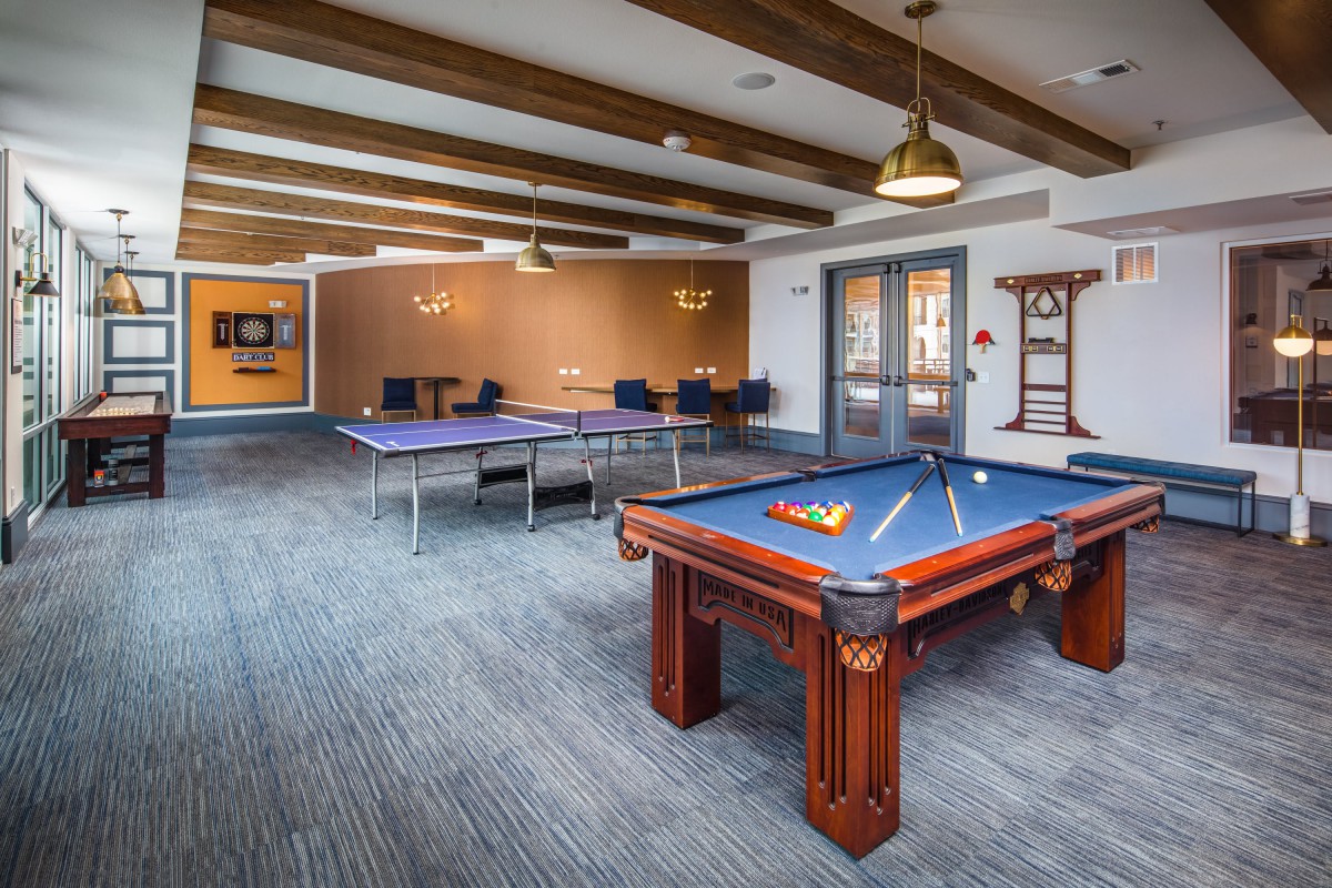 A modern game room featuring a pool table and ping pong tables for recreation.